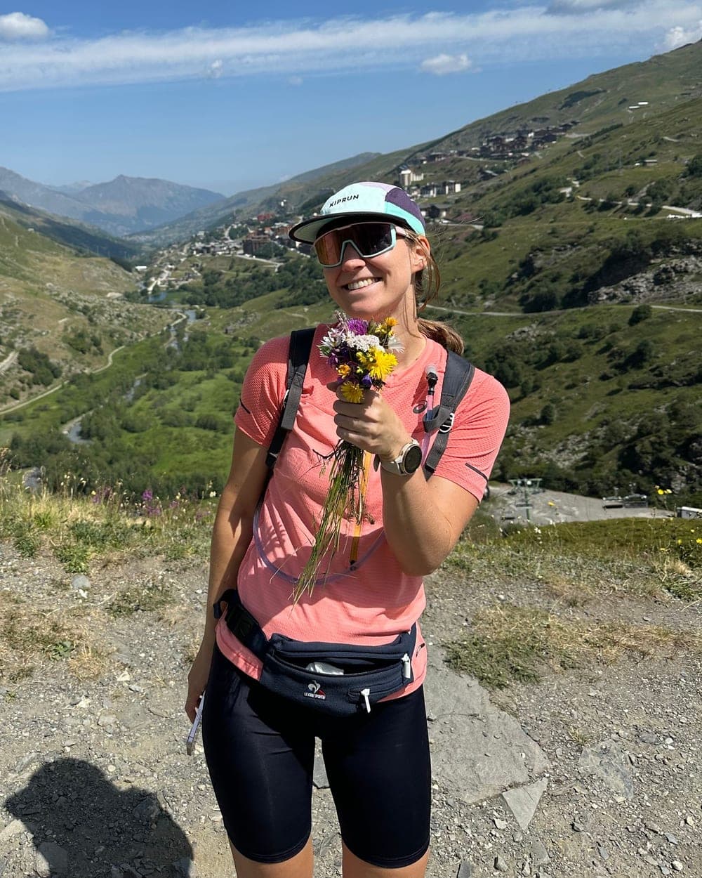 Clémence en randonnée en montagne, souriante, un bouquet de fleurs sauvages à la main